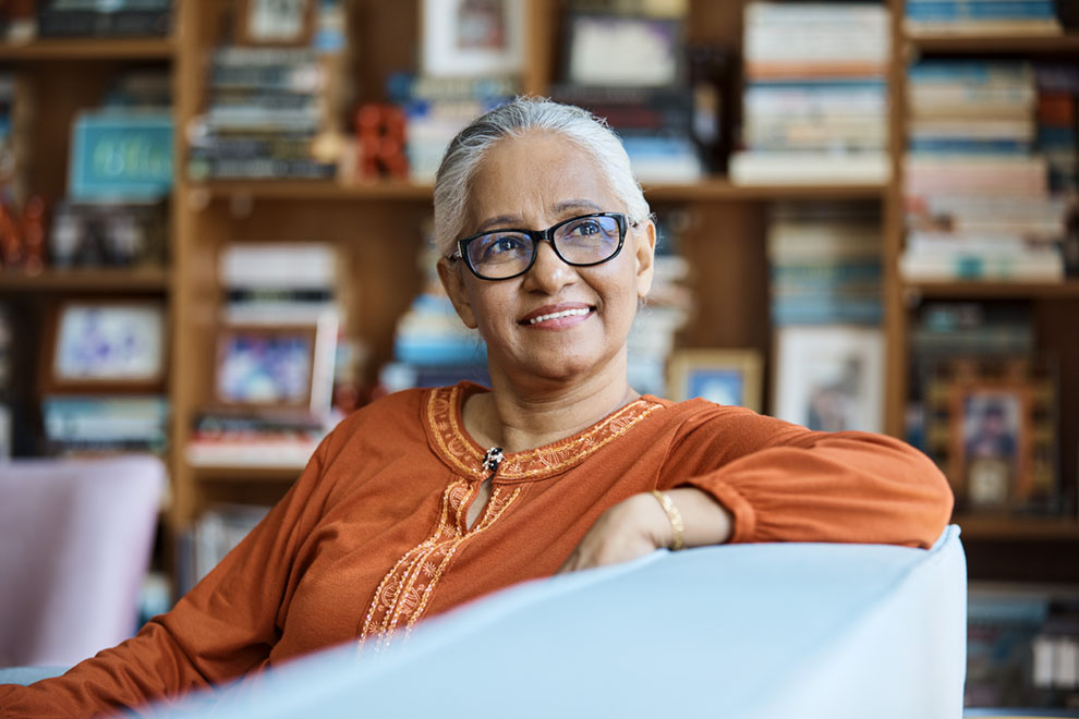 Thoughtful senior woman sitting on sofa at home