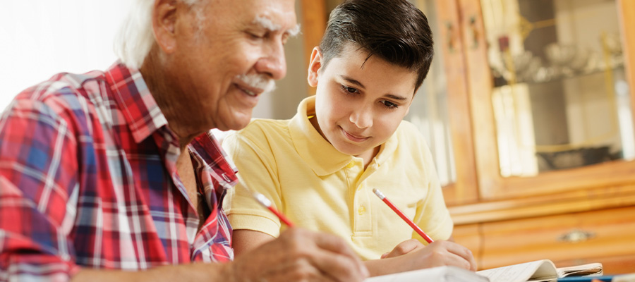 Older man helps a young male student with homework