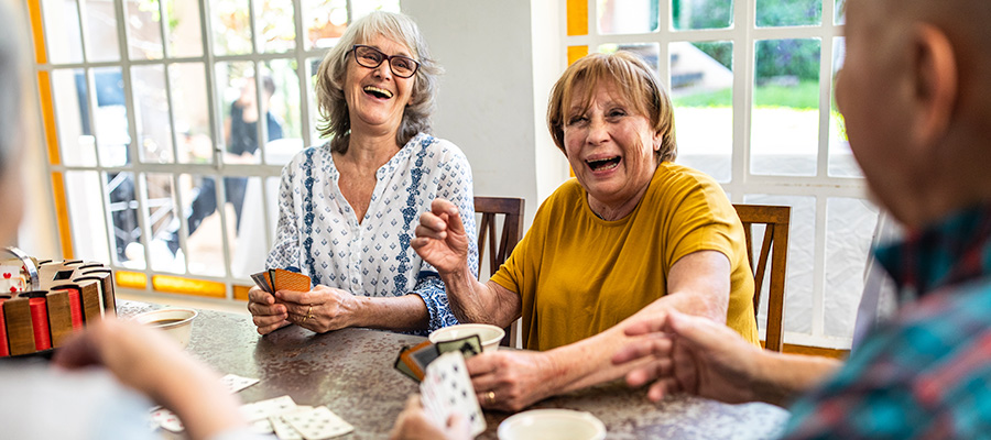 Senior citizens laugh while playing cards