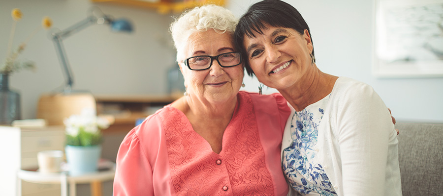 Two women sit on a sofa and smile